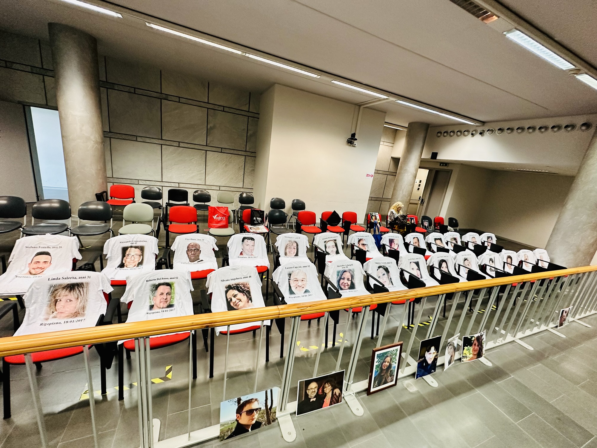 Aula giudiziaria con fotografie e magliette commemorative delle vittime della tragedia di Rigopiano
